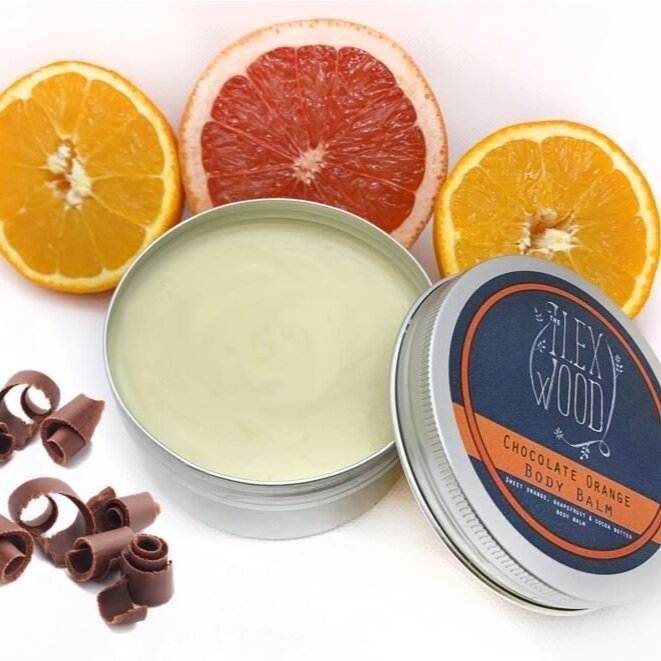Open tin of Ilex Wood Chocolate Orange Body Balm with orange and grapefruit slices and chocolate curls around it